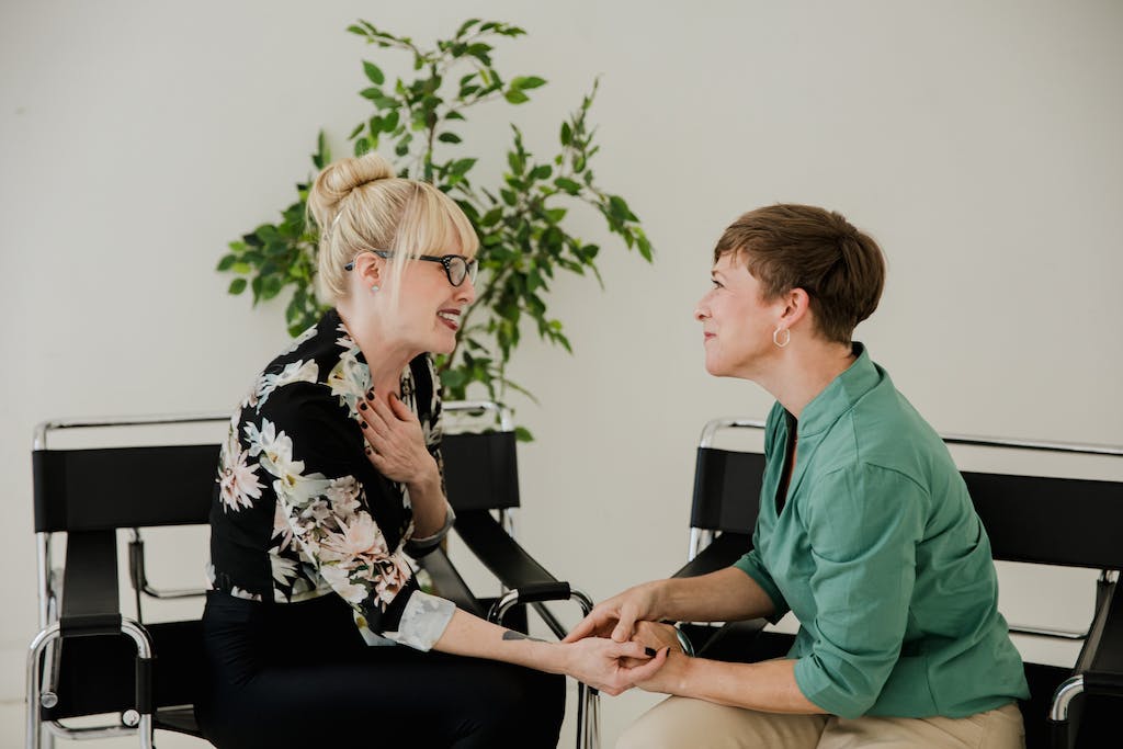 Women Sitting on Black Chairs Facing Each Other while Having a Conversation