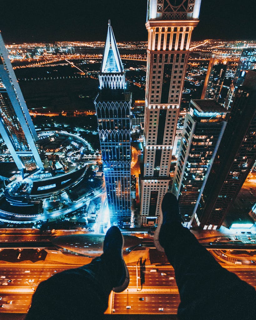 Person Sitting on Top of a Skyscraper in City Downtown