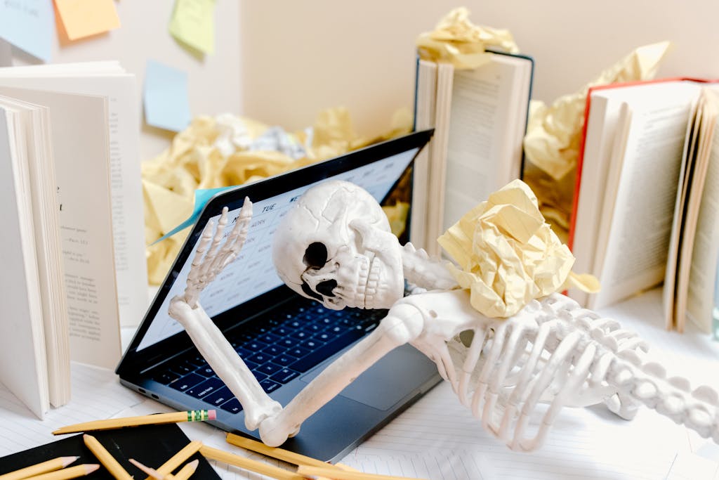 White Skeleton Figurine on Black Laptop Computer